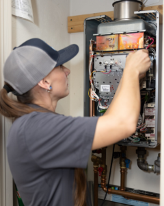 A technician servicing a tankless water heater for a customer at Powell's of Wilmington, NC
