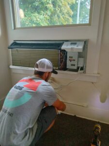 A technician from 406 Heating & Cooling LLC servicing a window AC unit in Missoula, MT.