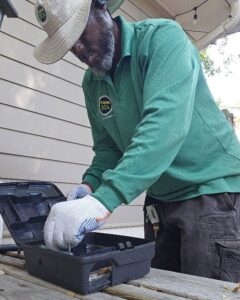 A Mosquito Joe of Columbia technician setting up a pest bait station for rodent or insect control in Columbia, SC.