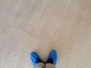 A Dirt Busters, Inc. technician wearing protective shoe covers on a clean carpet, demonstrating care during service in Anaheim, CA.