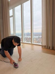 A technician from Cosmo Carpet Cleaning spot cleaning a light-colored carpet in a high-rise apartment in Princeton, NJ.