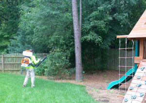 A technician using a backpack sprayer to treat a backyard for pest control at Clifft Lawn & Pest Management in Jonesboro, AR.