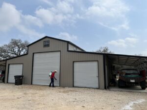 A Blessed Pest Control technician applying an exterior pest treatment to a barn or garage building in San Antonio, TX