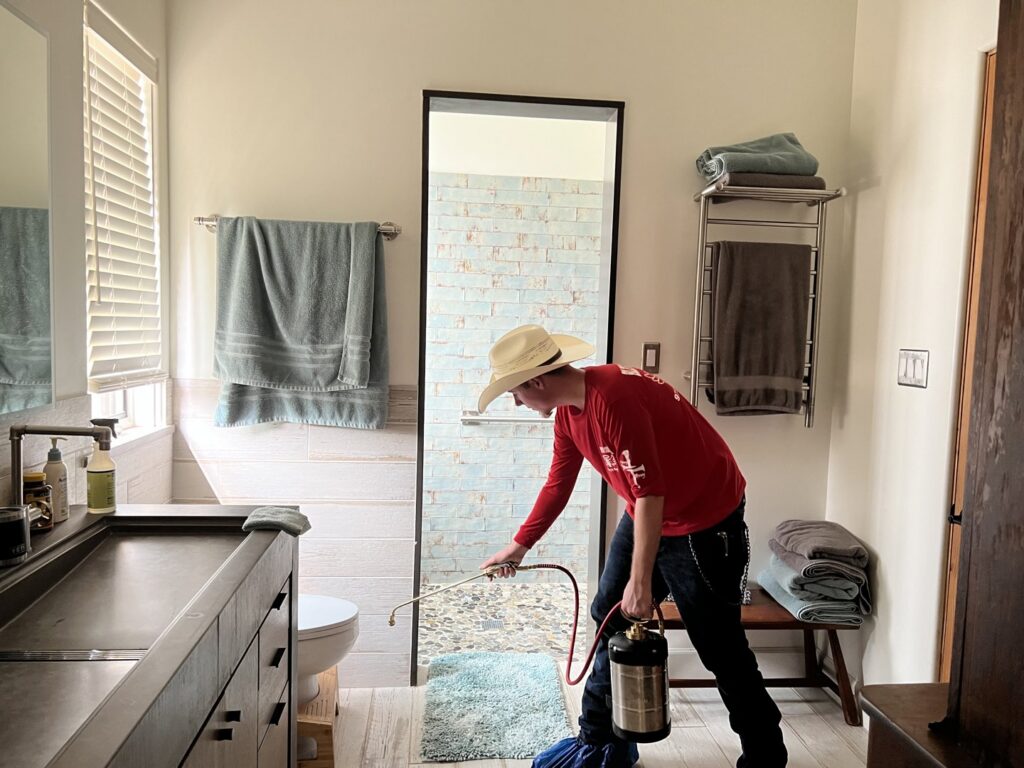 A Blessed Pest Control technician performing an indoor pest treatment in a bathroom in San Antonio, TX