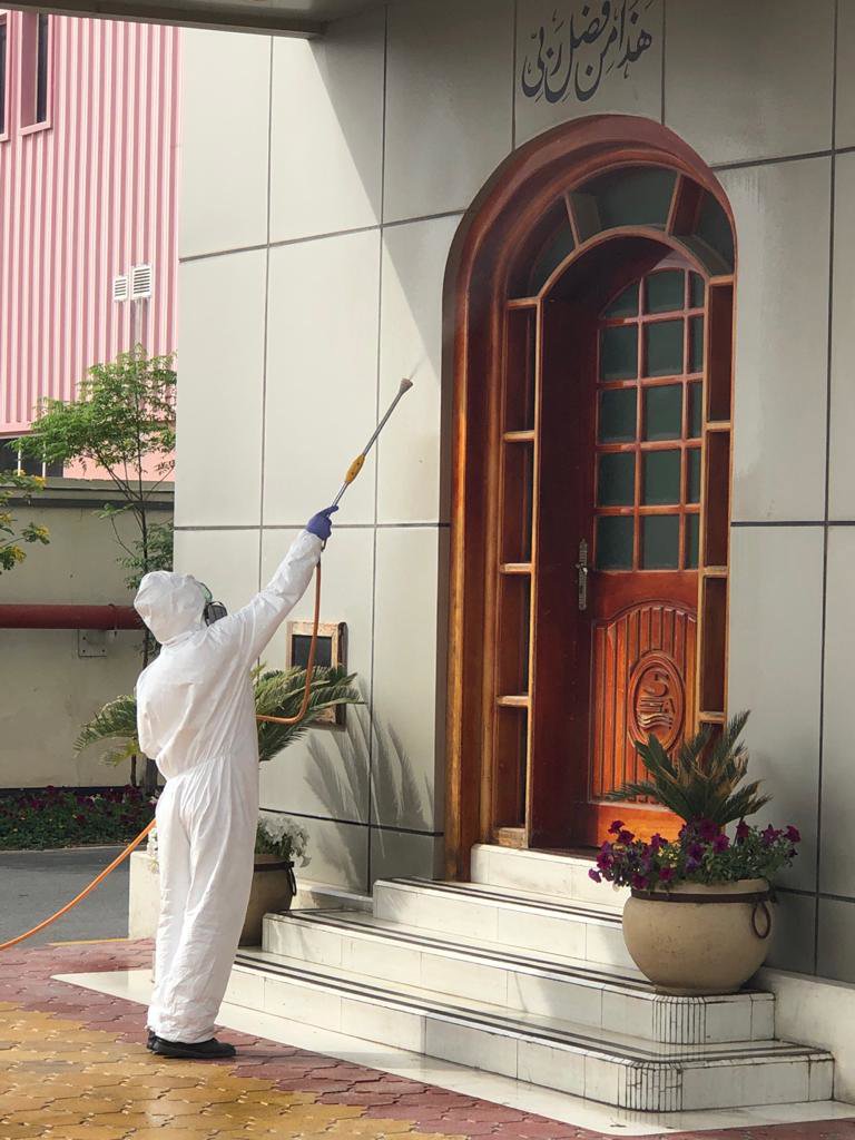 A Matar Termite & Pest Control technician in a hazmat suit sprays the exterior of a building in Alexandria, VA.