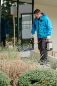 A Pest Lock, Inc. technician applying pest control treatment to the exterior of a building in Vancouver, WA.