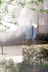 A Mosquito Boss technician spraying bushes with pest control treatment in sunlight in Brandon, MS