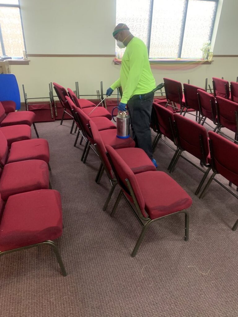 A technician spraying chairs with a treatment solution in a hall, demonstrating services by Pest 2 Rest Pest Control LLC in Milwaukee, WI.