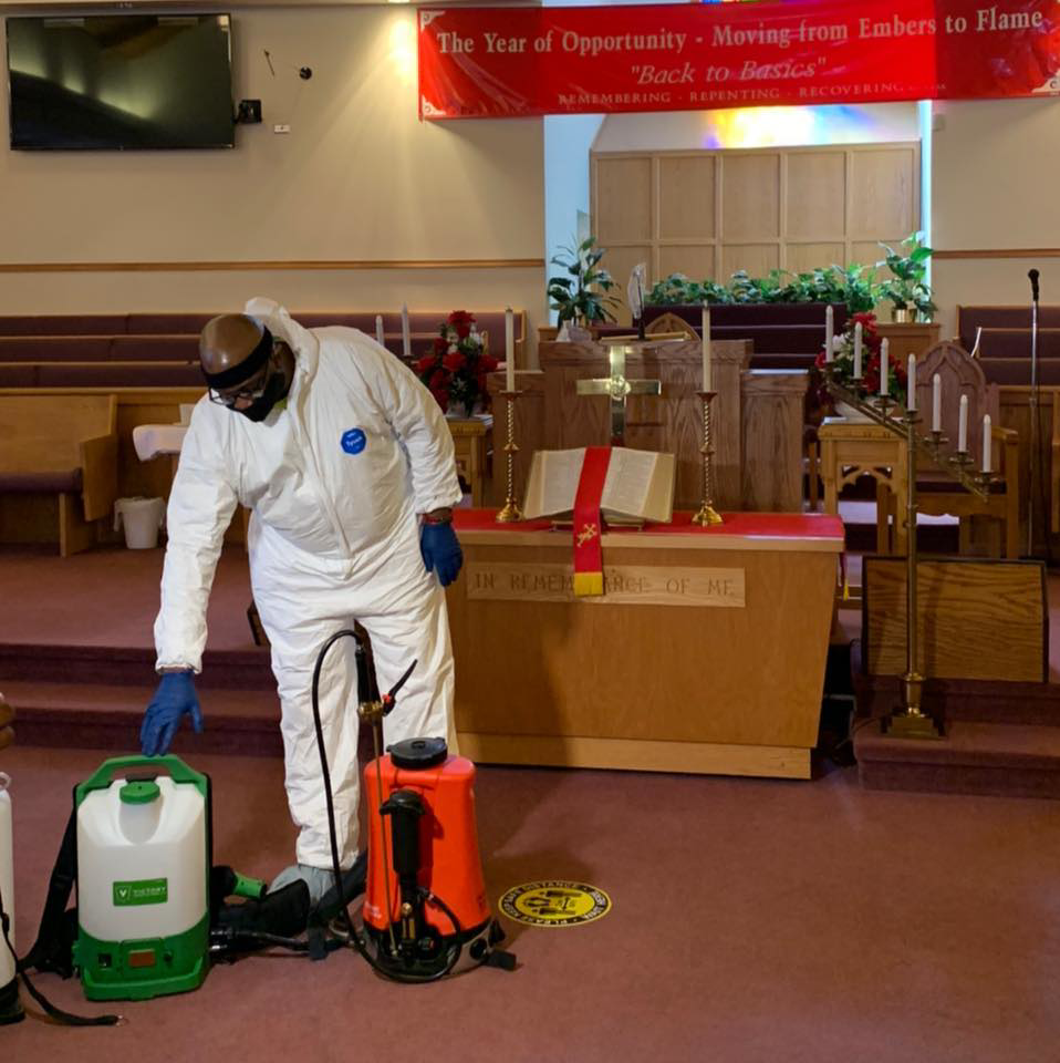 A technician in a hazmat suit using a sprayer for sanitization in a church, a service provided by Pest 2 Rest Pest Control LLC in Milwaukee, WI.