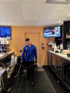 An Ideal Pest Control Inc technician performing pest treatment in a commercial bar area in Miami, FL.