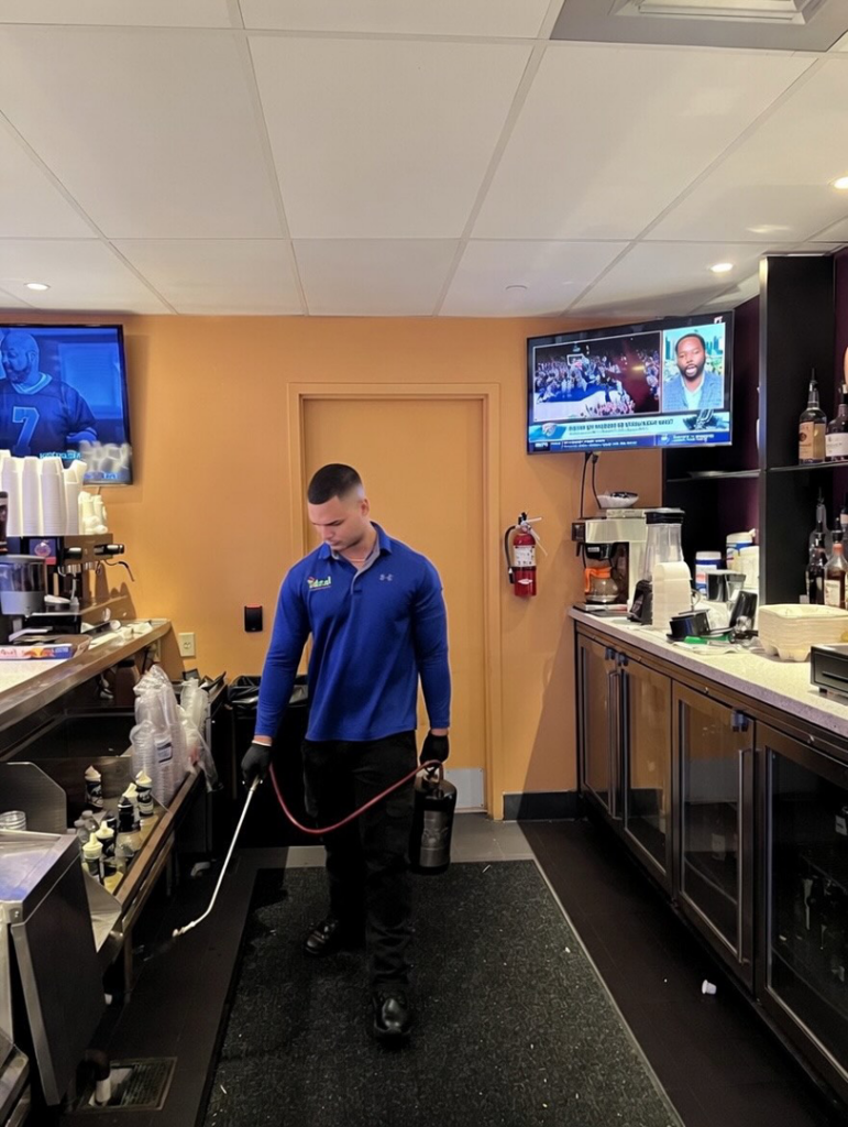 An Ideal Pest Control Inc technician performing pest treatment in a commercial bar area in Miami, FL.
