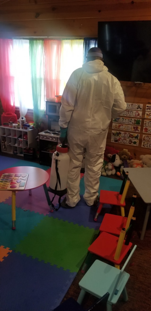 A technician in a hazmat suit using a sprayer for sanitization in a daycare room, a service provided by Pest 2 Rest Pest Control LLC in Milwaukee, WI.