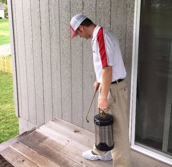 A technician from Laser Pest Management, Inc. spraying a deck or patio area for pest control in Eudora, KS.