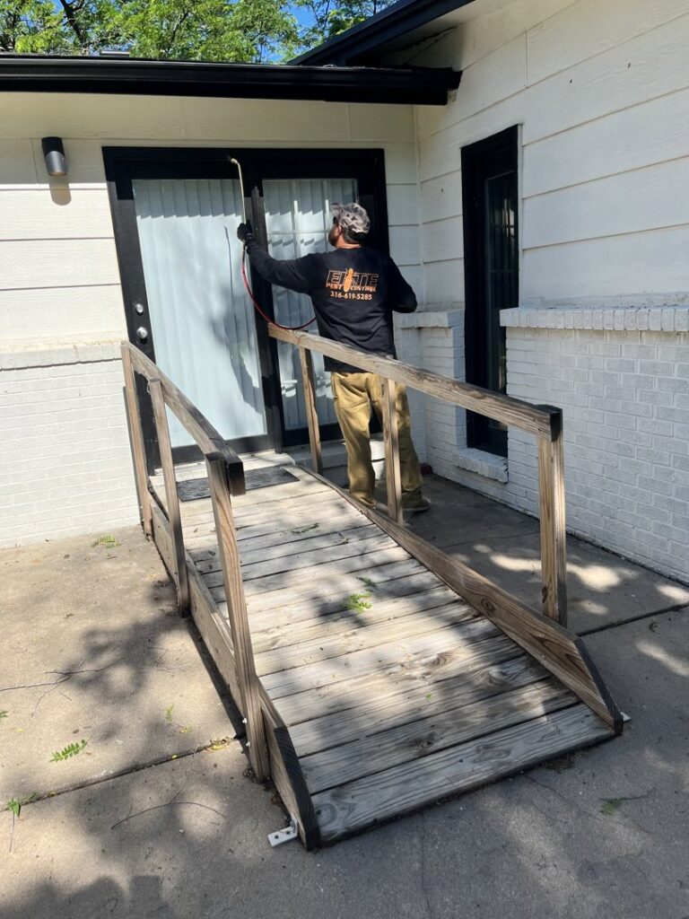 An Elite Pest Control technician spraying a doorway and exterior area for pests in Maple Grove, MN.