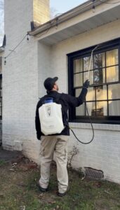 A Pest Management Systems, Inc. technician applying pest control treatment to the exterior of a home in Greensboro, NC
