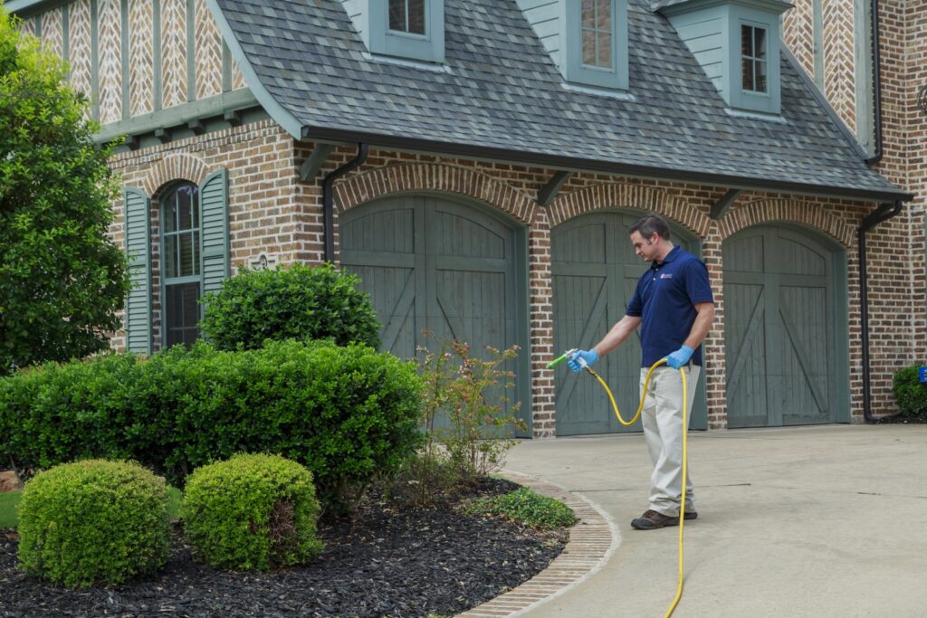 A Berrett Pest Control Denver technician spraying liquid pest treatment around a home's exterior in Denver, CO.