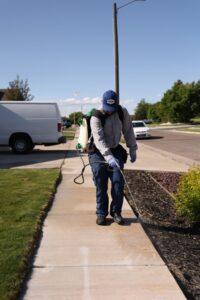 A Prompt Pest Solutions technician spraying the exterior perimeter of a property for pest control in Pocatello, ID.