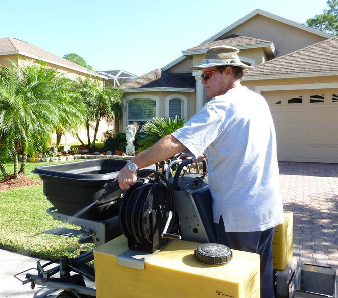 A technician spraying for pest control around a residential home by Allstate Termite and Pest Control Inc. in Tampa, FL.