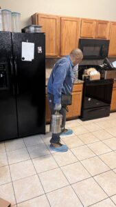 A D' Bug Man Pest Control technician applying pest treatment in a residential kitchen in Arlington, TX.