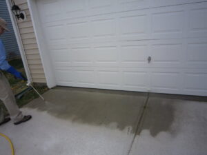 A Stomp Pest Control technician spraying the perimeter near a garage door for pest control in Raleigh, NC.