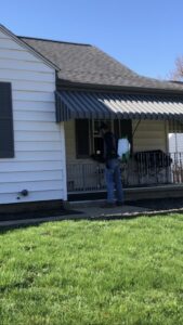 A technician using a backpack sprayer to treat the exterior of a house for pests by Antix Pest Control in Canton, OH.