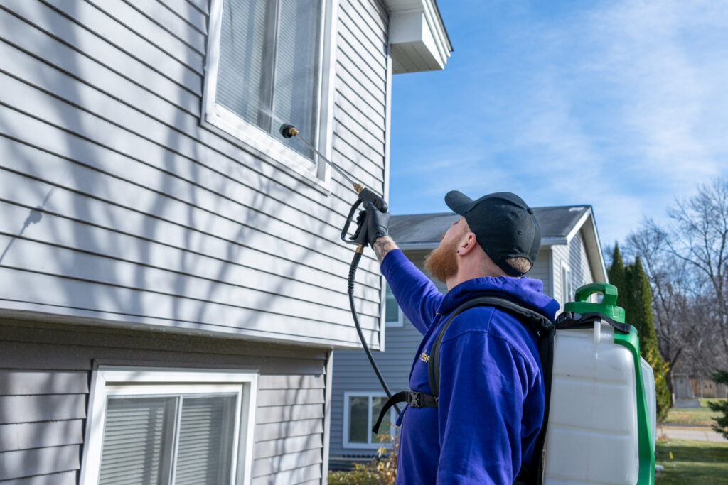 A technician spraying the exterior of a house for pest control at Abra Kadabra Pest and Wildlife in Forest Lake, MN.