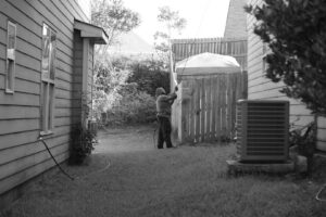 A technician spraying the exterior of a house with a long wand, performing pest control for Direct Pest Solutions Of Georgia, LLC in McDonough, GA.