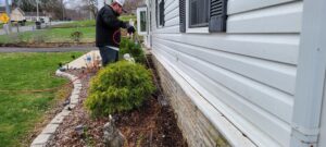 A pest control technician spraying the exterior foundation of a residential home for pest prevention by Pest In Class Exterminating in Johnson City, TN.