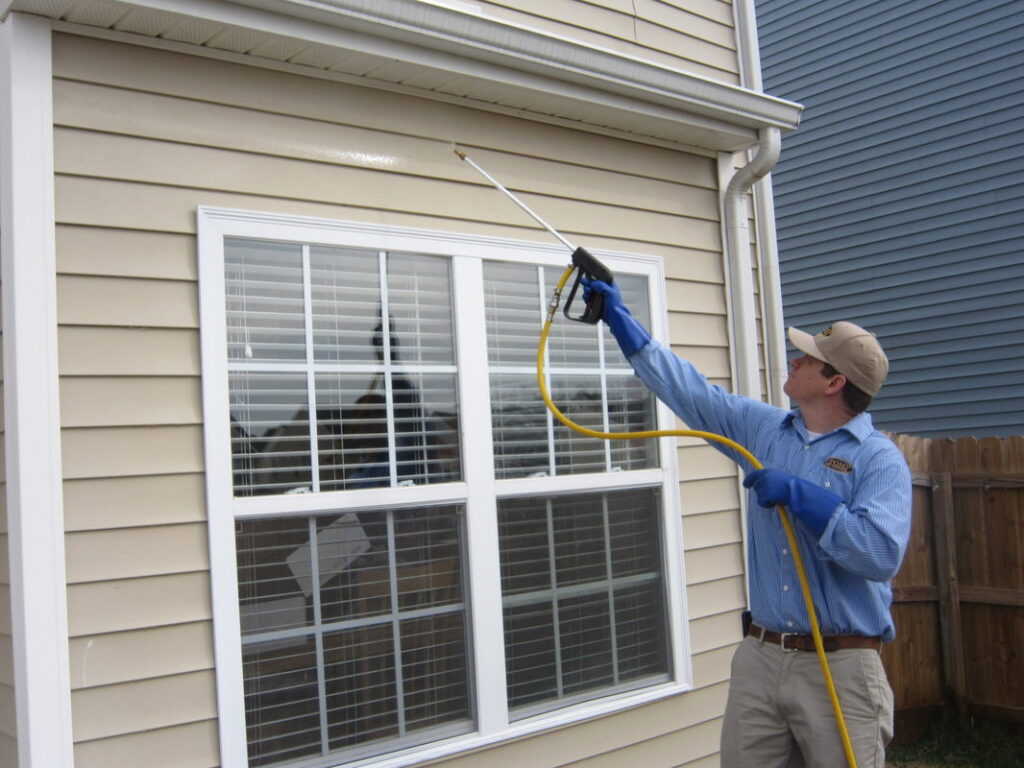A Stomp Pest Control technician spraying the exterior siding of a house for pest prevention in Raleigh, NC.