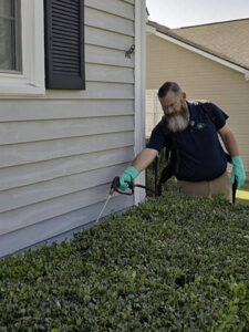 A Pest Magic Pest Control technician spraying the foundation of a house for pest prevention in Forsyth, GA.