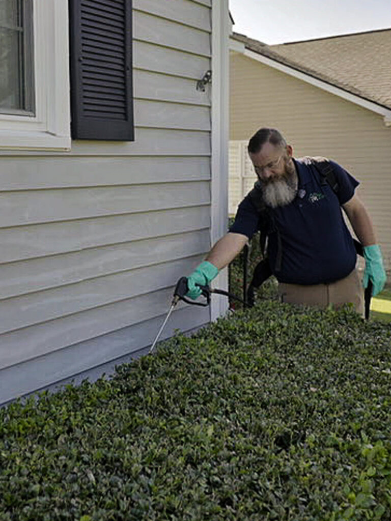 A Pest Magic Pest Control technician spraying the foundation of a house for pest prevention in Forsyth, GA.