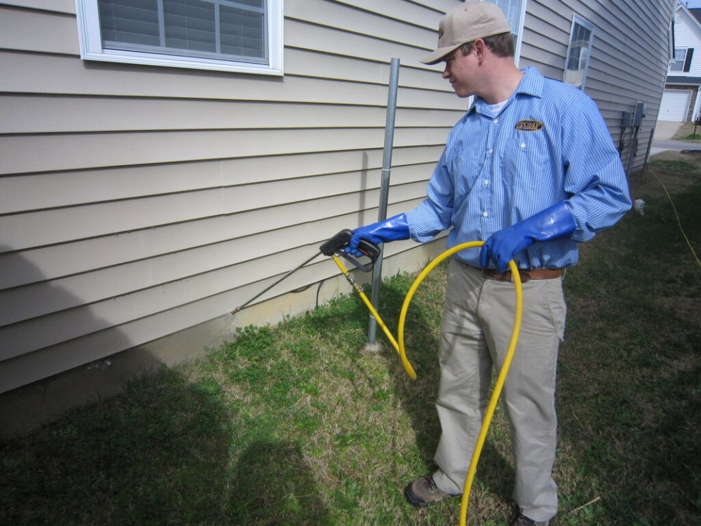 A Stomp Pest Control technician spraying the foundation of a residential home for pest control in Raleigh, NC.