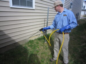 A Stomp Pest Control technician spraying the foundation of a residential home for pest control in Raleigh, NC.