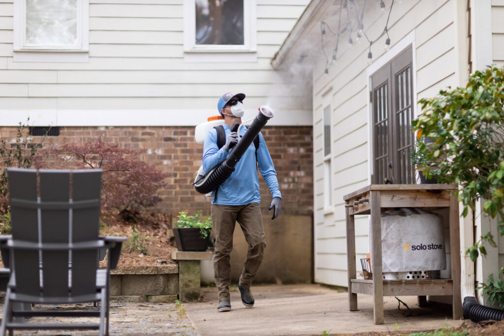 A Mosquito Boss technician spraying the side of a house and patio area for pest control in Brandon, MS