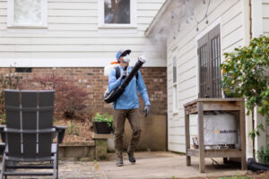 A Mosquito Boss technician spraying the side of a house and patio area for pest control in Brandon, MS
