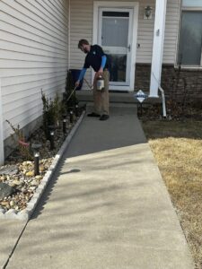 A technician from Perimeter Pest Control DSM spraying the perimeter of a house in Des Moines, IA, performing pest control service.