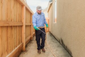 A Thrive Pest Pros technician spraying pest control treatment along the perimeter of a house in Clovis, CA.