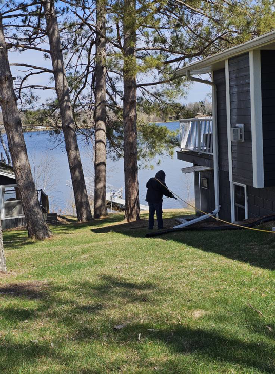 A technician spraying the exterior of a house for pest control by BugMeisters North in Lindstrom, MN