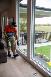 A Miller Pest & Termite technician spraying indoors along windows for pest control in Kansas City, MO