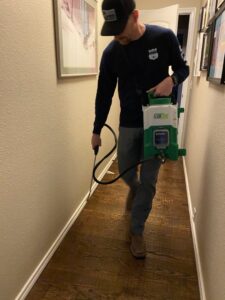 A Blue Line Pest Police technician spraying baseboards inside a home for pest control in Fort Worth, TX.
