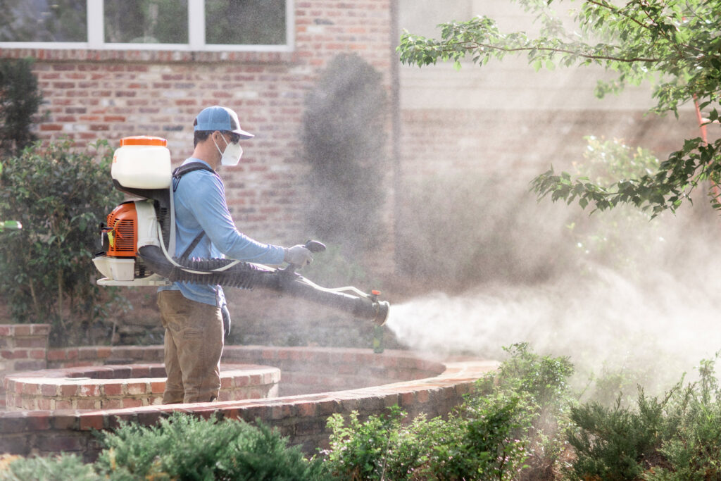 A Mosquito Boss technician spraying landscaping and bushes for pest control in Brandon, MS