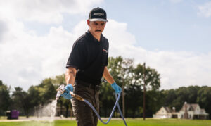 A pest control technician spraying liquid treatment on a residential lawn for The Pest Detective in Cleveland, OH.