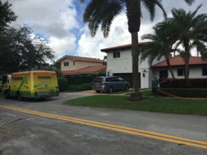 A PowerX Pest Control of South Florida technician spraying a lawn in front of a house in Miami, FL.