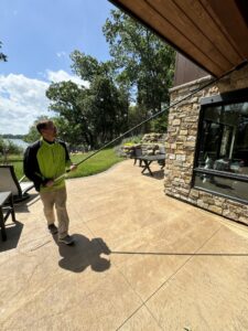 A Green Harmony technician performing pest control treatment near a patio and lake in Oconomowoc, WI.