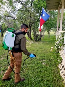 A technician from Rat King Pest Control spraying the perimeter of a house for pest control in San Antonio, TX.