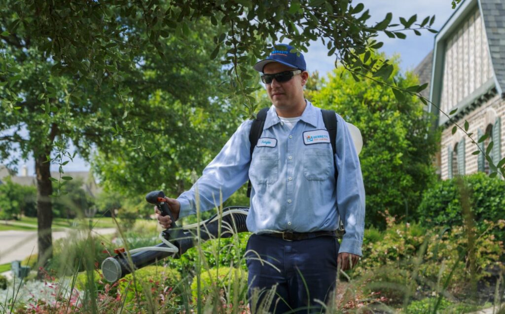 A Berrett Pest Control Denver technician spraying pest control treatment in a landscaped area in Denver, CO.