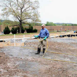 A technician spraying pre-construction termite treatment at a building site for Curry's Termite, Pest & Animal Control in Little Rock, AR