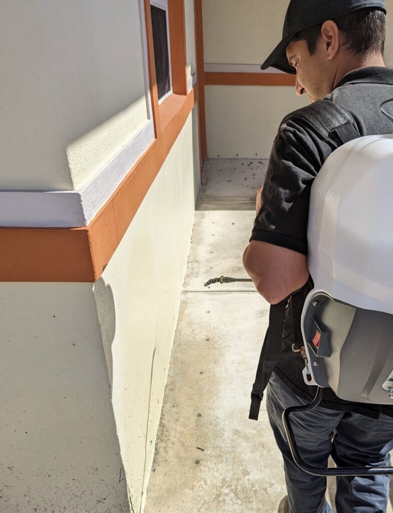 A technician spraying the side of a building for pest control at Nexterminate in Hollywood, FL.