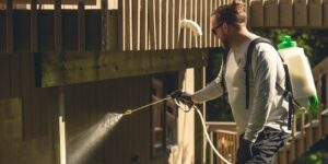 A technician spraying under a deck for pest control at Abra Kadabra Pest and Wildlife in Forest Lake, MN.