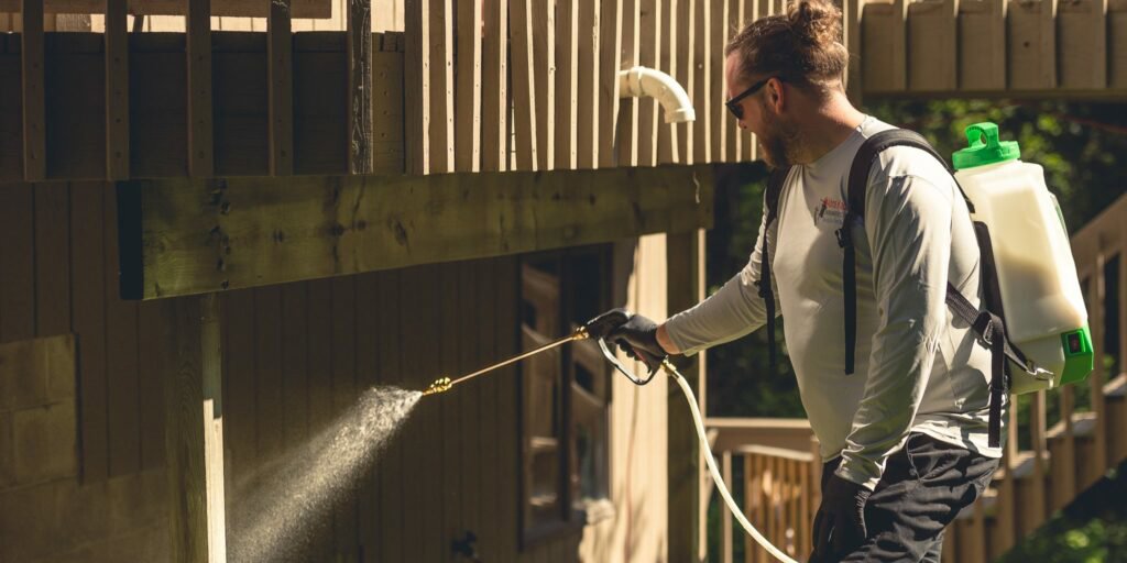 A technician spraying under a deck for pest control at Abra Kadabra Pest and Wildlife in Forest Lake, MN.